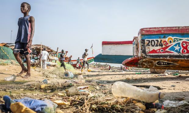 a group of people standing near a boat on the beach